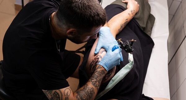 Mejores tatuadores - Tatuador realizando un tatuaje a un hombre reconocido como uno de los mejores tatuadores en Barcelona