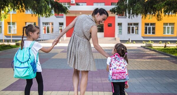 Colegios privados - Mujer llevando de la mano a dos niñas a una escuela privada en Barcelona