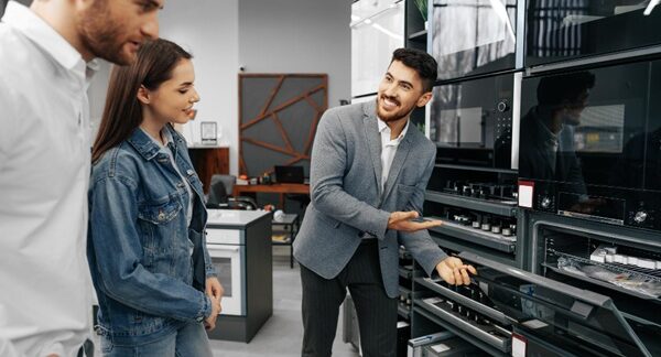 Tiendas de electrodomésticos - Vendedor de tienda de electrodomésticos ofreciendo aparatos eléctricos y utensilios del hogar a una pareja en una de las mejores tiendas de electrodomésticos en Barcelona