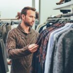 Ropa para hombre - Hombre en una tienda para caballero observando las prendas para comprar ropa en una de las mejores tiendas de ropa para hombre de Barcelona