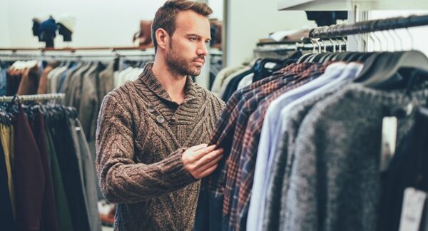 Ropa para hombre - Hombre en una tienda para caballero observando las prendas para comprar ropa en una de las mejores tiendas de ropa para hombre de Barcelona