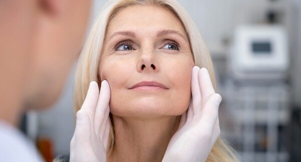 Clínicas de lifting facial - Médico estético evaluando el rostro de una mujer para realizar un tratamiento de rejuvenecimiento facial en la mejor clínica estética Barcelona
