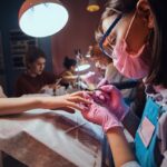 Salones de uñas - Especialista en estética de uñas realizando manicura a una mujer en uno de los mejores salones de uñas de Barcelona