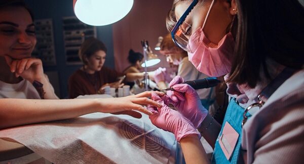 Salones de uñas - Especialista en estética de uñas realizando manicura a una mujer en uno de los mejores salones de uñas de Barcelona